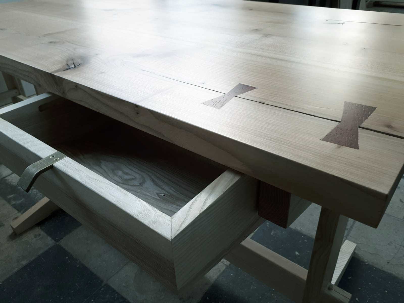 Birou cu sertarul deschis și mâner de alamă în prim plan