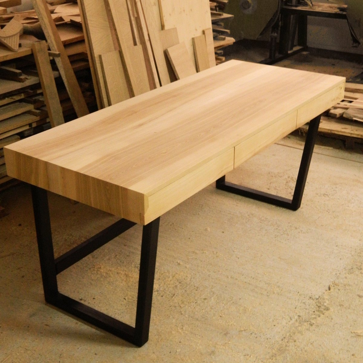 Birou din lemn de frasin cu picioare negre, vedere generală, în atelierul de tâmplărie