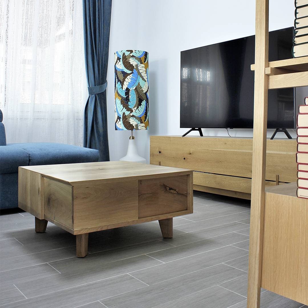 Masă de cafea joasă din stejar masiv cu patru picioare, vedere de ansamblu în living cu canapele și comodă TV