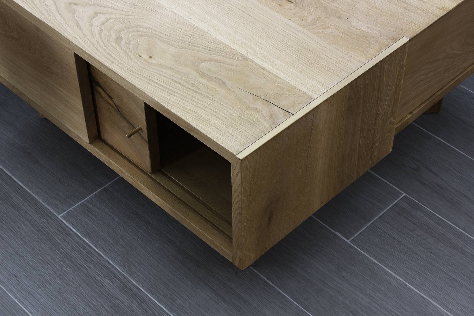 Masă de cafea din stejar masiv, vedere în prim plan cu muchiile teșite ale blatului și rafturi de depozitare dedesubt cu uși glisante