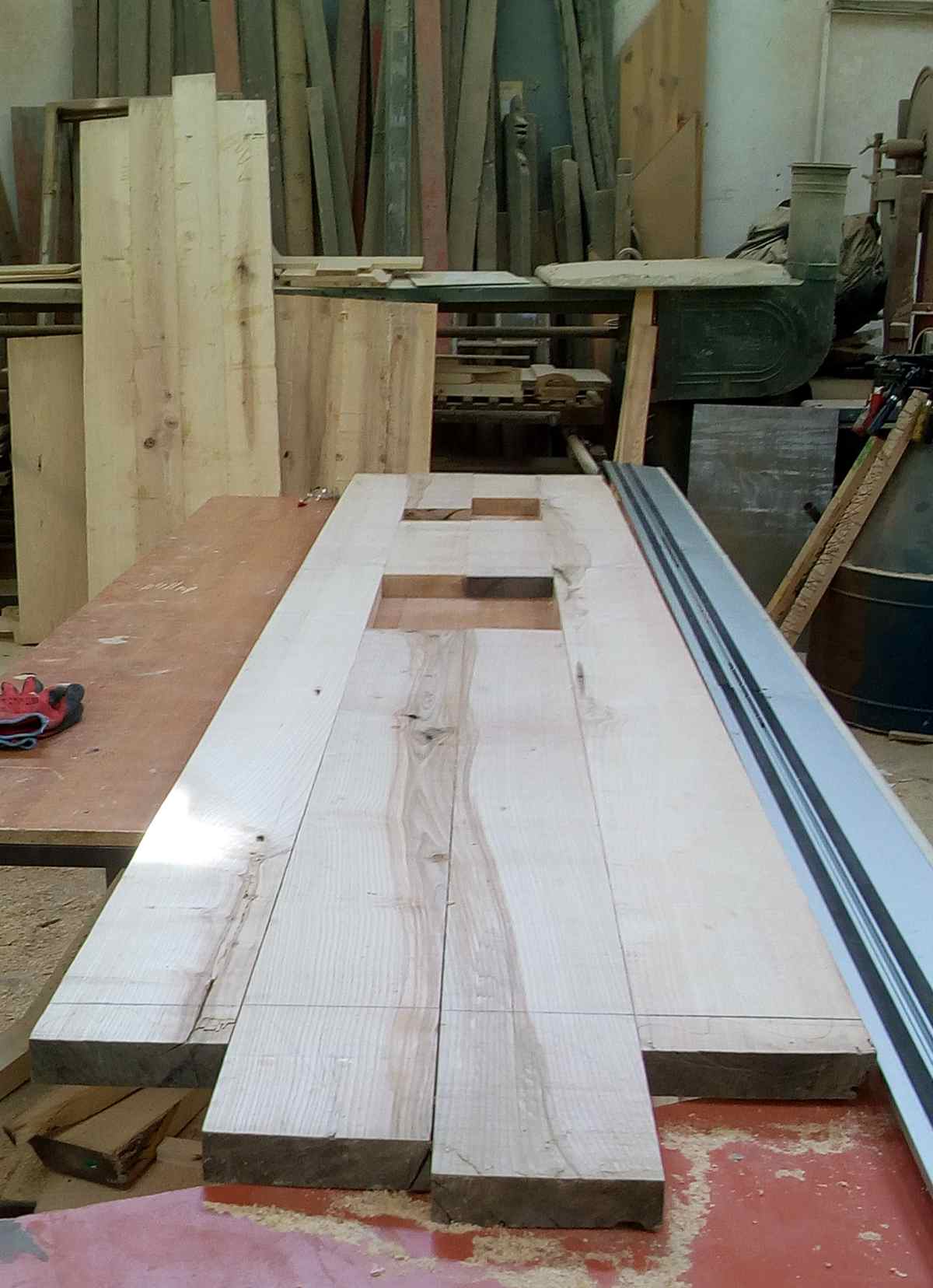 Imagine din atelier de tamplarie cu scanduri groase din lemn de frasin ce alcatuiesc blatul de bucatarie cu decupajele pentru plita si chiuveta.