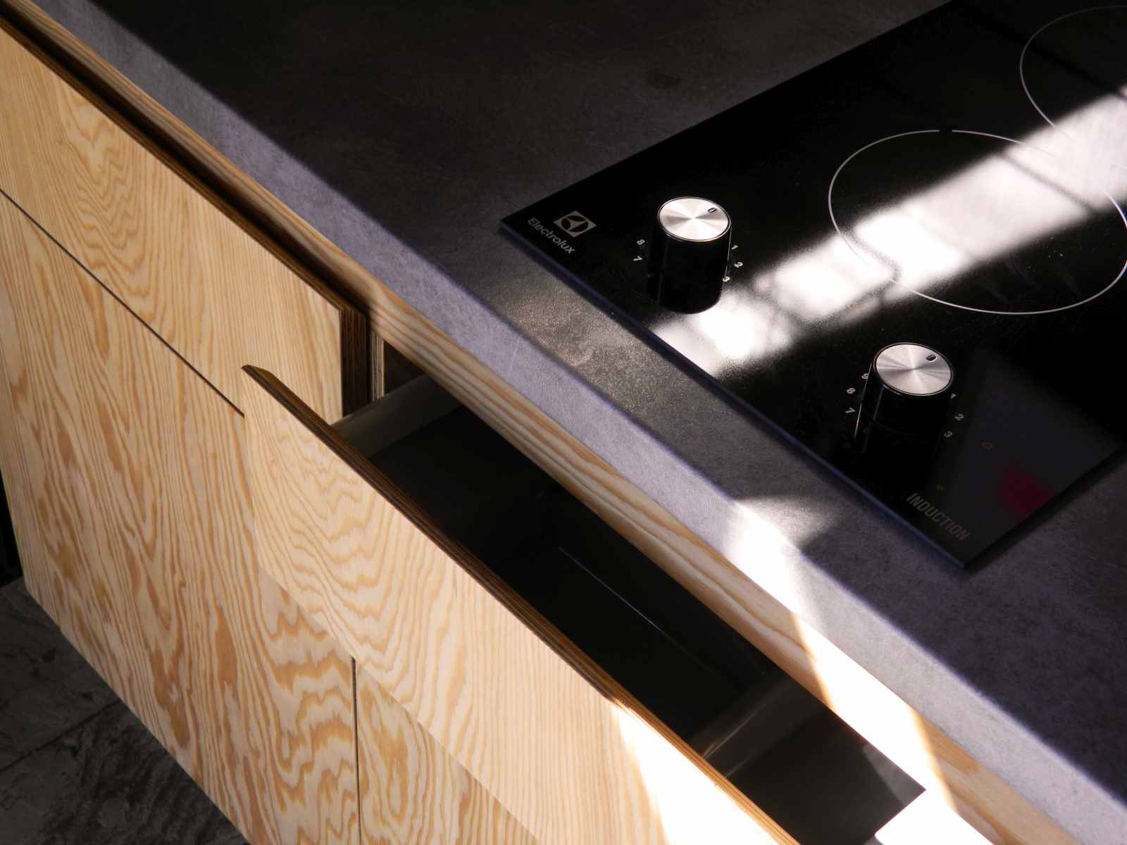 Sertar deschis cu maner tesit, usi din placaj cu finisaj natural, si blat cu plita cu inductie