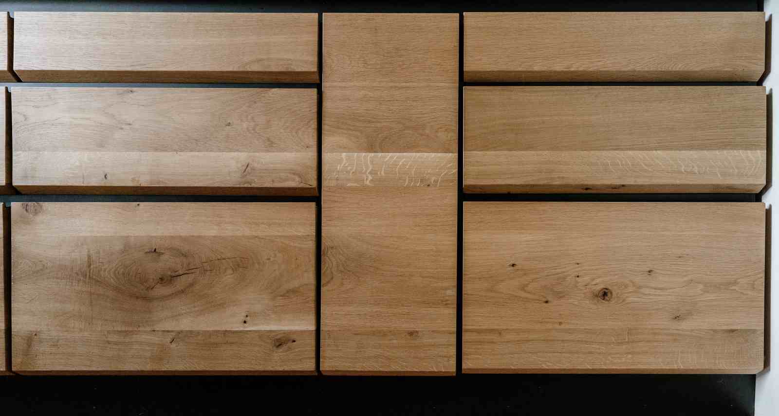 Vedere de aproape cu sertare si front inalt din lemn de stejar rosturi negre, fibra naturala a lemnului se continua de pe o placa pe alta