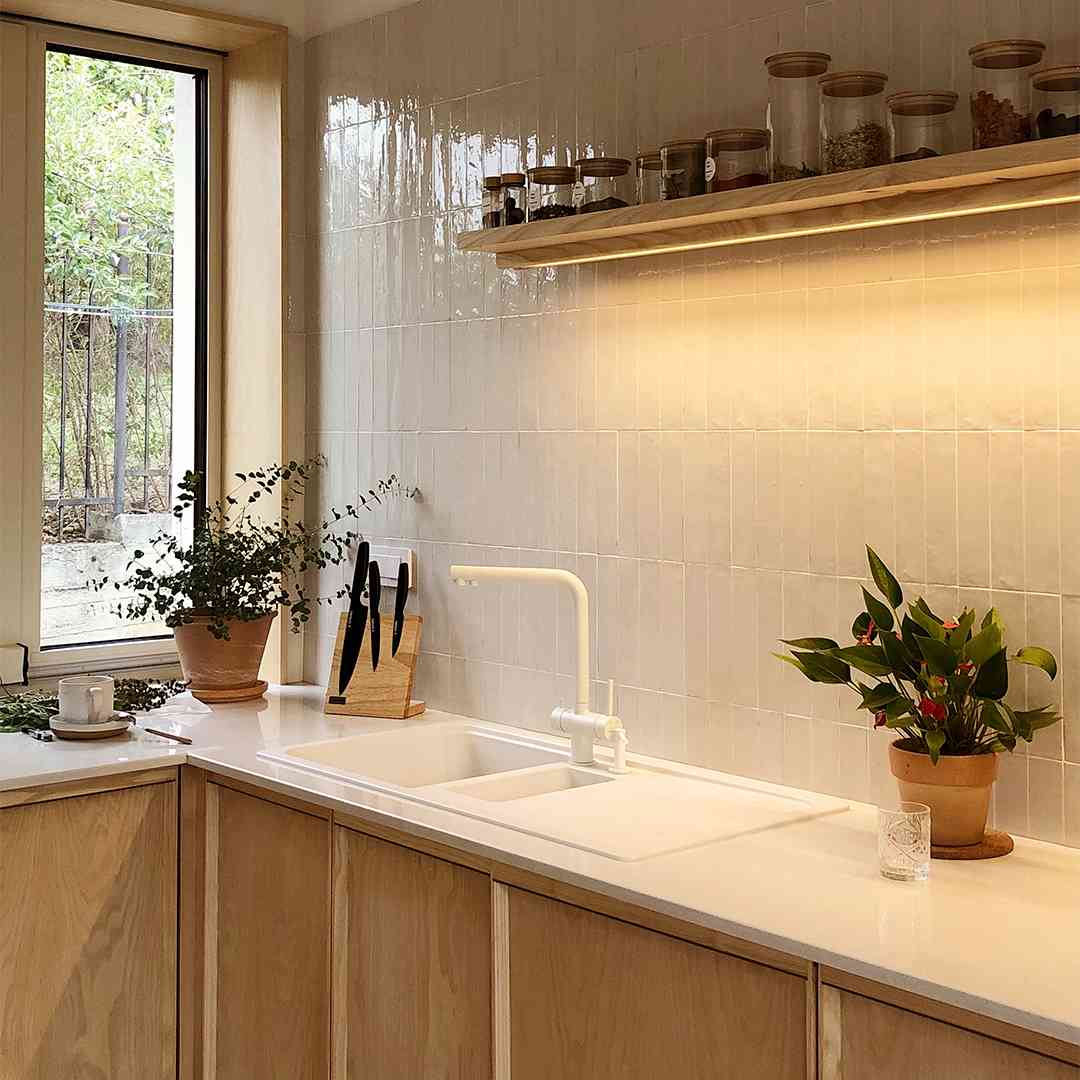 vedere din coltul bucatariei, inspre fereastra, cu ghiveci de flori si suport de cutite pe blat. Usile mobilei au margini in relief si maner integrat in rama